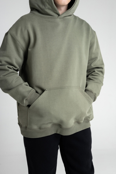 Эта толстовка для настоящих мужчин изготовлена из очень плотного футера 490 г/м², что обеспечивает надежность и долговечность. Оверсайз фасон и прямой силуэт создают комфортный и стильный образ, а длина до середины бедра добавляет универсальности. Большой объемный капюшон из трех деталей с декоративной отстрочкой швов придает модели уникальный характер, а шов втачивания капюшона по спинке аккуратно закрыт киперной лентой для дополнительного комфорта. Накладной карман-кенгуру на полочке добавляет практичности. Втачные рукава с манжетами и притачной пояс из футера или кашкорсе обеспечивают идеальную посадку. Декоративная отстрочка по плечевым швам, пройме, а также швам притачивания манжет и пояса шириной 0,5 мм подчеркивает внимание к деталям. Эта толстовка станет отличным выбором для тех, кто ценит качество и стиль.