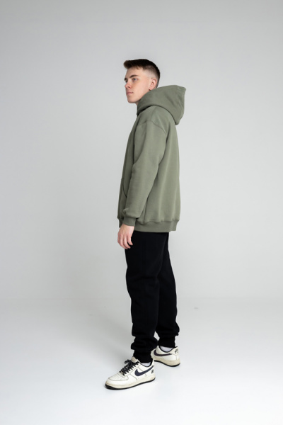 Эта толстовка для настоящих мужчин изготовлена из очень плотного футера 490 г/м², что обеспечивает надежность и долговечность. Оверсайз фасон и прямой силуэт создают комфортный и стильный образ, а длина до середины бедра добавляет универсальности. Большой объемный капюшон из трех деталей с декоративной отстрочкой швов придает модели уникальный характер, а шов втачивания капюшона по спинке аккуратно закрыт киперной лентой для дополнительного комфорта. Накладной карман-кенгуру на полочке добавляет практичности. Втачные рукава с манжетами и притачной пояс из футера или кашкорсе обеспечивают идеальную посадку. Декоративная отстрочка по плечевым швам, пройме, а также швам притачивания манжет и пояса шириной 0,5 мм подчеркивает внимание к деталям. Эта толстовка станет отличным выбором для тех, кто ценит качество и стиль.