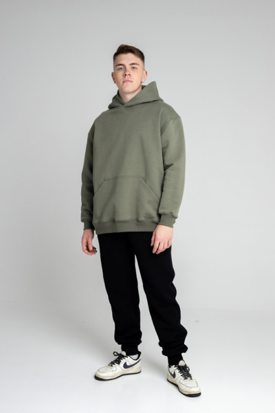 Эта толстовка для настоящих мужчин изготовлена из очень плотного футера 490 г/м², что обеспечивает надежность и долговечность. Оверсайз фасон и прямой силуэт создают комфортный и стильный образ, а длина до середины бедра добавляет универсальности. Большой объемный капюшон из трех деталей с декоративной отстрочкой швов придает модели уникальный характер, а шов втачивания капюшона по спинке аккуратно закрыт киперной лентой для дополнительного комфорта. Накладной карман-кенгуру на полочке добавляет практичности. Втачные рукава с манжетами и притачной пояс из футера или кашкорсе обеспечивают идеальную посадку. Декоративная отстрочка по плечевым швам, пройме, а также швам притачивания манжет и пояса шириной 0,5 мм подчеркивает внимание к деталям. Эта толстовка станет отличным выбором для тех, кто ценит качество и стиль.